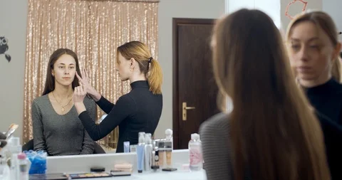 Makeup artist makes makeup to young girl and applies a cream Stock Footage 126129403