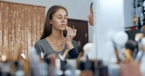 Makeup artist makes makeup to young girl and applies a cream Stock Footage 126129410