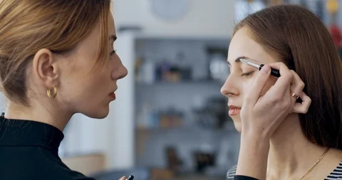 Makeup artist makes makeup to young girl and combs eyebrows Stock Footage 126129451