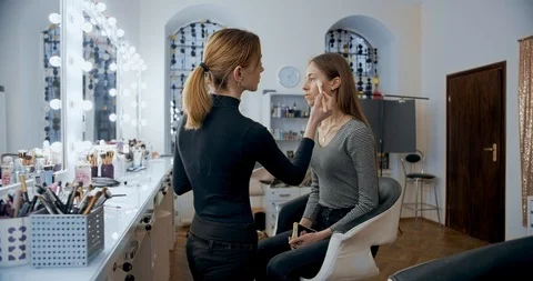 Makeup artist makes makeup to young girl face and applies a color sculpting Видео 126180801