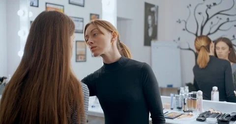 Makeup artist makes makeup to young girl face and applies a color sculpting Stock Footage 126181356