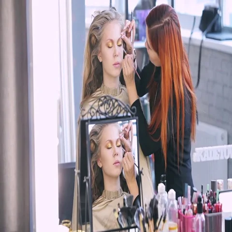 Makeup artist makes models eye makeup. Hairdresser makes hairstyle for model Stock Footage 69546182