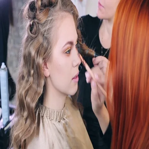 Makeup artist makes models eye makeup. Hairdresser makes hairstyle for model Stock Footage 69546223