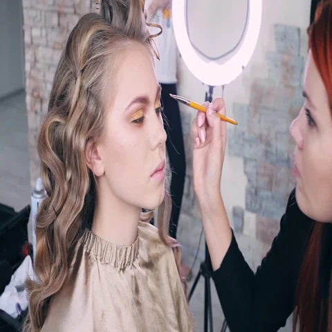 Makeup artist makes models eye makeup. Hairdresser makes hairstyle for model Stock Footage 69546329