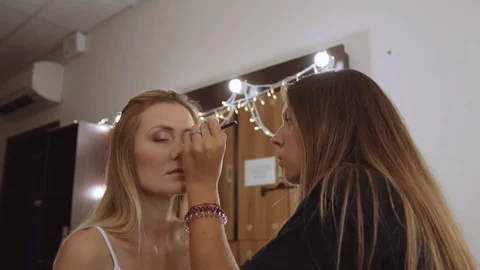 Makeup artist makes models eye makeup. Beautiful young woman make-up with a Video stock 81046871