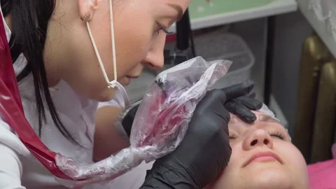 Makeup artist makes permanent makeup of eyebrows to young client woman in beauty Stock Footage 169287717
