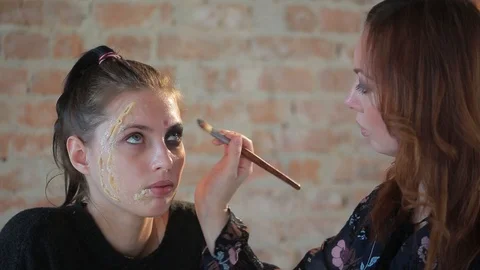 Makeup artist makes wax plastic makeup for art cinema and paints face of girl Video stock 105599586