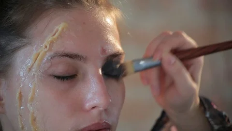Makeup artist makes wax plastic makeup for art cinema and paints face of girl Video stock 105599602