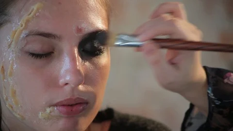 Makeup artist makes wax plastic makeup for art cinema and paints face of girl Video stock 105599649
