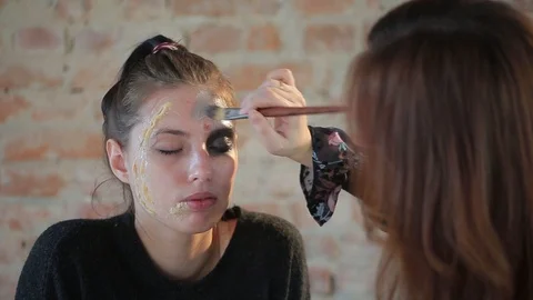 Makeup artist makes wax plastic makeup for art cinema and paints face of girl Stock Footage 105599655