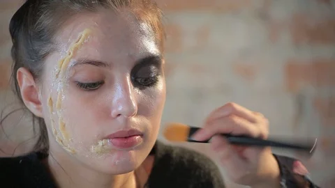 Makeup artist makes wax plastic makeup for art cinema and paints face of girl Video stock 105599706