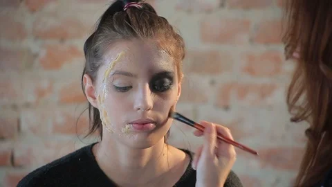 Makeup artist makes wax plastic makeup for art cinema and paints face of girl Video stock 105599779
