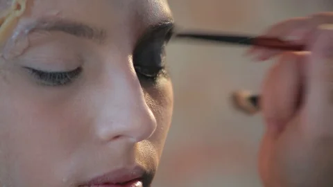 Makeup artist makes wax plastic makeup for art cinema and paints face of girl Stock Footage 105599794