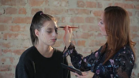 Makeup artist makes wax plastic makeup for art cinema and paints face of girl Stock Footage 105599831