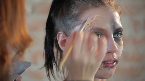 Makeup artist makes wax plastic makeup for art cinema and paints face of girl Video stock 105599861