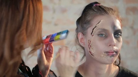 Makeup artist makes wax plastic makeup in form of bloody wound on face of girl Video stock 105599887