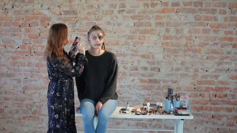 Makeup artist makes wax plastic makeup in form of bloody wound on face of girl Stock Footage 105599963