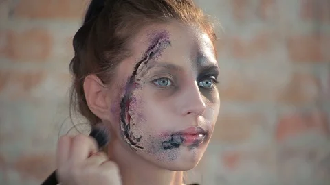 Makeup artist makes wax plastic makeup in form of bloody wound on face of girl Video stock 105600000