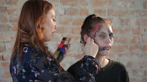 Makeup artist makes wax plastic makeup in form of bloody wound on face of girl Stock Footage 105600002