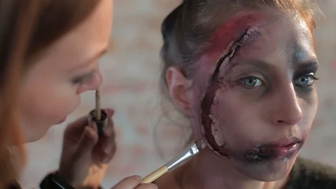 Makeup artist makes wax plastic makeup in form of bloody wound on face of girl Video stock 105600010