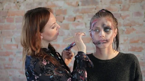 Makeup artist makes wax plastic makeup in form of bloody wound on face of girl Video stock 105600035