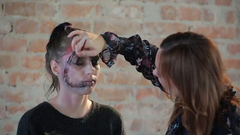 Makeup artist makes wax plastic makeup in form of bloody wound on face of girl Stock Footage 105600066