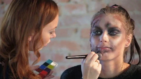 Makeup artist makes wax plastic makeup in form of bloody wound on face of girl Video stock 105600091