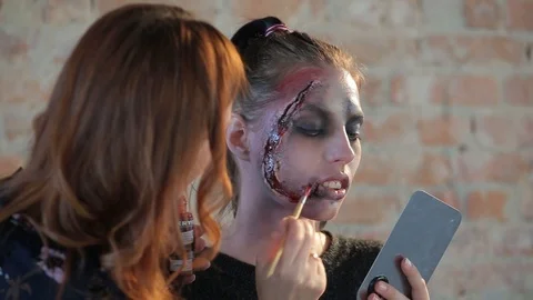 Makeup artist makes wax plastic makeup in form of bloody wound on face of girl Video stock 105600122