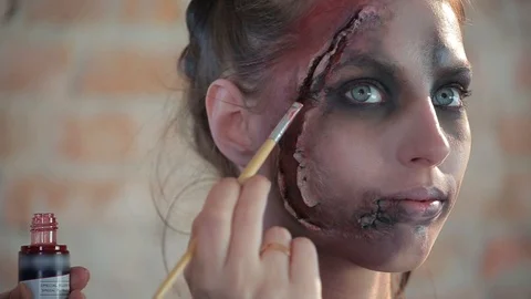 Makeup artist makes wax plastic makeup in form of bloody wound on face of girl Video stock 105600129