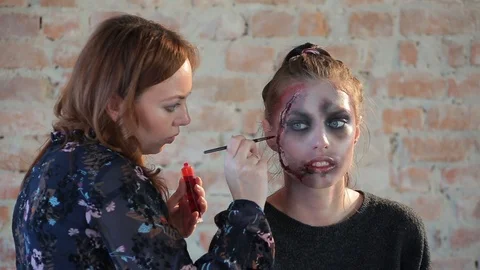 Makeup artist makes wax plastic makeup in form of bloody wound on face of girl Stock Footage 105600170