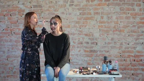 Makeup artist makes wax plastic makeup in form of bloody wound on face of girl Stock Footage 105600180