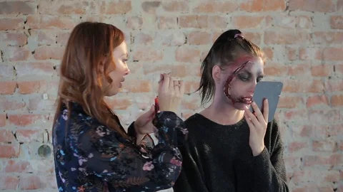 Makeup artist makes wax plastic makeup in form of bloody wound on face of girl Video stock 105600182