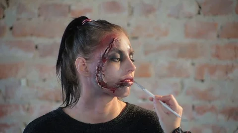 Makeup artist makes wax plastic makeup in form of bloody wound on face of girl Stock Footage 105600216