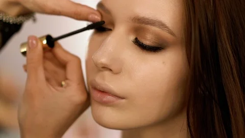 Makeup artist making eye-makeup for young model 4k Stock Footage 111380309