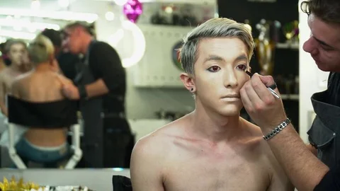 Makeup artist making face art for a young man in front of the mirror Video stock 76577767