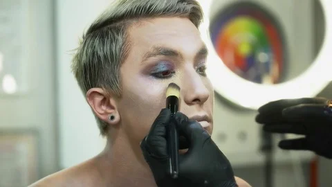 Makeup artist making face art for a man with a makeup brush closeup Stock Footage 76580729