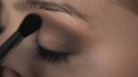 Makeup artist making professional make-up for young woman in beauty studio. Make Stock Footage 128185879