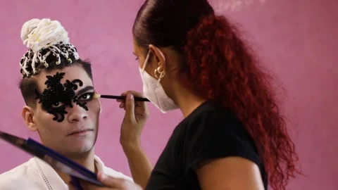 Makeup artist with a mask putting makeup on a man for halloween Stock Footage 142169167
