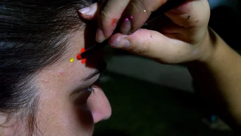 Makeup artist painting red dots on caucasian middle age woman. Stock Footage 123726151