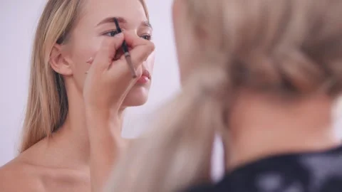 The makeup artist paints the eyebrows of the model Stock-Footage 142135117