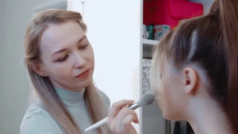 Makeup artist paints the model and smiles. Uses a large makeup brush. Stock Footage 149684835