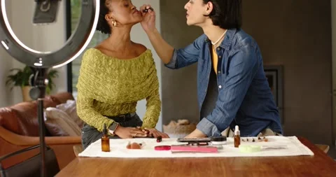 Makeup artist picking lipstick tilting client's chin applying under ring light Stock Footage 337294100
