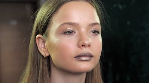 Makeup artist puts glitter on the face and eye of teenager girl in beauty salon Stock Footage 132381121