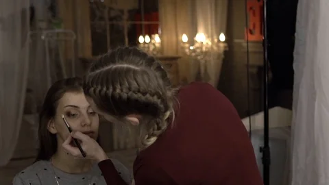 Makeup artist puts shadows on the model on the background of light bulbs Vídeo Stock 85756303
