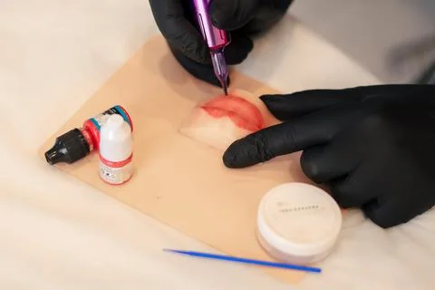 Makeup artist trying to do permanent makeup on silicone lips Stock Photos