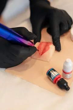 Makeup artist trying to do permanent makeup on silicone lips Stock Photos