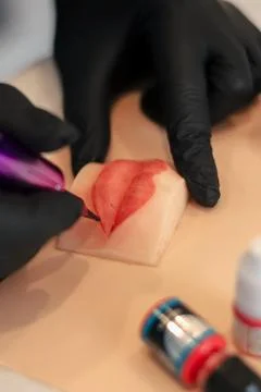 Makeup artist trying to do permanent makeup on silicone lips Stock Photos