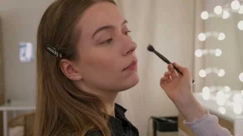 Makeup artist uses brushes and applies foundation to the model's face. Video stock 199839194