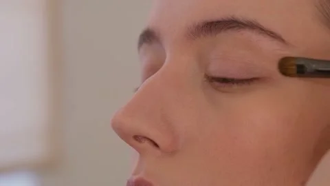 Makeup artist uses brushes and applies foundation to the model's face. Stock Footage 199839270