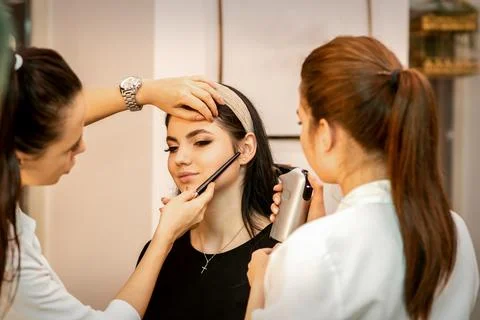 Makeup artist using an airbrush on the face of a young caucasian woman in a Stock-Fotos